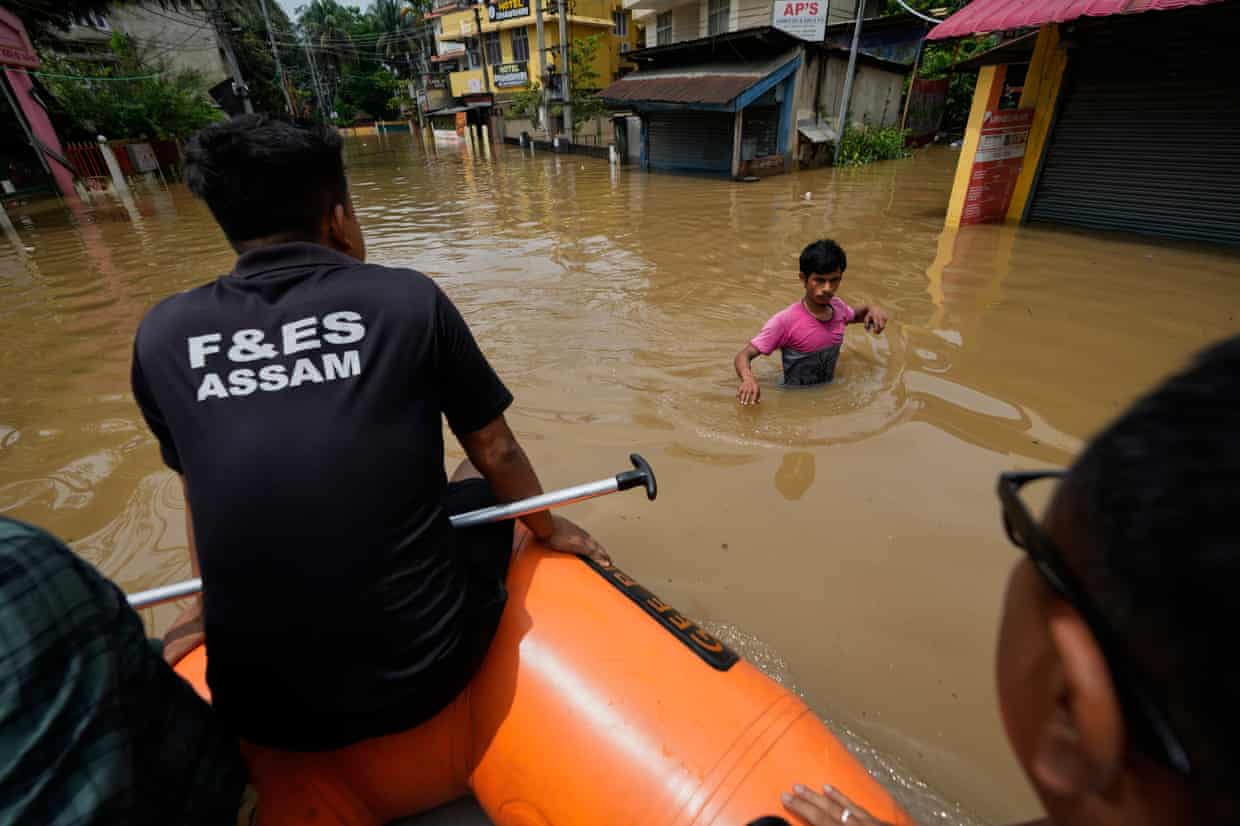 Rescue teams reach a man wading through flood water after heavy monsoon rain in Guwahati, India.