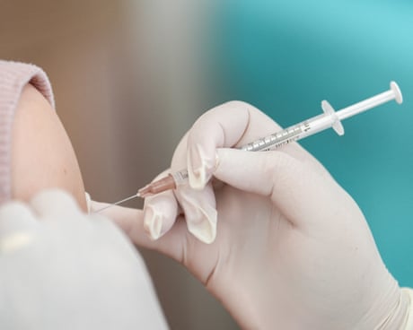 gloved hand injects vaccines into a person's arm