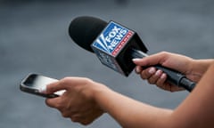 a person holds a smartphone and a microphone with 'Fox News' branding