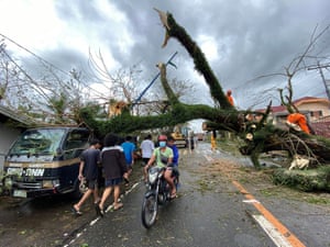 Filipinos pass under a toppled tree in the typhoon-hit town. Super typhoon Goni, with winds forecast to reach 249km/h (154mph), made landfall in the provinces of Albay and Camarines Sur