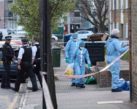 Uniformed police officers and investigators in blue overalls in a residential street
