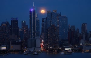 Weehawken, US. The moon rises behind the skyline of midtown Manhattan and the Empire State Building in New York City, as seen from New Jersey