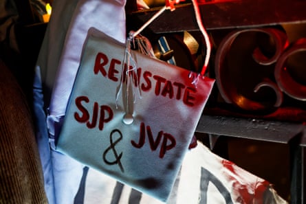 A person holds a graduation cap that reads “reinstate SJP and JVP”