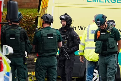 An armed police officer with members of the ambulance service at the scene of an incident at Heaton Park Hebrew Congregation synagogue in Crumpsall, Manchester.