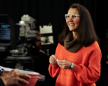Mary Peltola smiles in an orange sweater while holding a paper during a debate.
