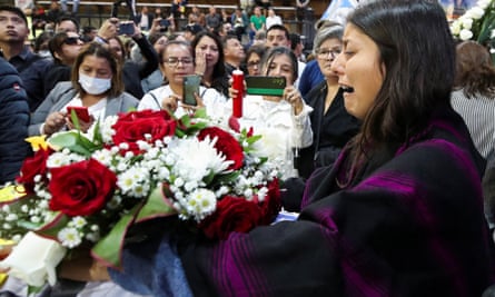 Weeping woman beside coffin piled with flowers