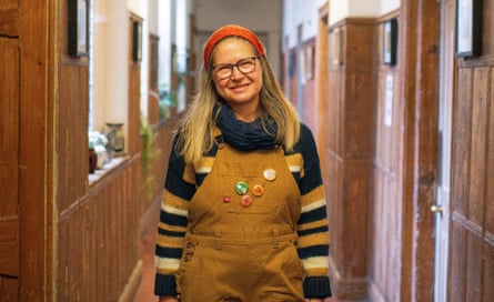 Dorit Schnieber wearing brown dungarees and a stripy jumper, in the long main hallway at Old Hall