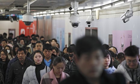 Commuters walk by surveillance cameras at a walkway between two subway stations in Beijing.