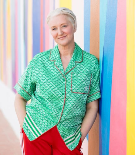 A woman with short grey hair, a green shirt and red trousers