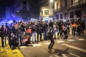 People take photos of a man throwing a bottle during clashes in Barcelona