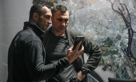 The mayor of Kyiv, Vitali Klitschko (right), and his brother Wladimir Klitschko look at a smart phone.