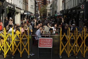 People react to being photographed as they sit outside on a street closed to traffic, so bars and restaurants can continue to stay open, in the Soho area of central London, on Saturday, 19 September 2020. Fresh nationwide lockdown restrictions in England appear to be on the cards soon as the British government targeted more areas Friday in an attempt to suppress a sharp spike in new coronavirus infections.