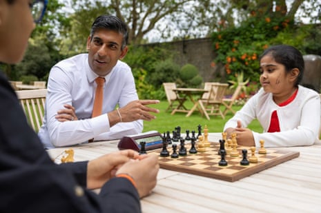 Rishi Sunak talks to two young people at a garden table with a chess set between them