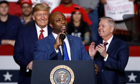 Tim Scott at a podium in front of Donald Trump