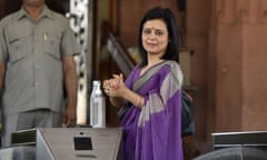 Mahua Moitra, wearing loose purple and silver robe-like dress, stands at an entrance to Parliament House, New Delhi, rubbing sanitiser onto her hands