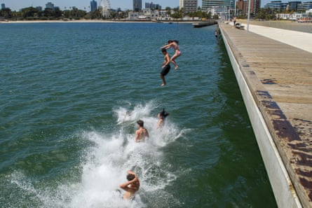 A group of young people leap from St Kilda Pier in Melbourne.
