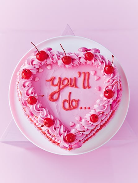 Heart shaped cake with pink buttercream and garnished with maraschino cherries.  the words 