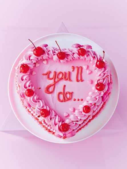 Heart shaped cake with pink buttercream and garnished with maraschino cherries. the words