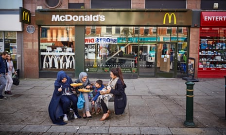 A group of women and a child eat in Oldham high street, 2016. Oldham town centre