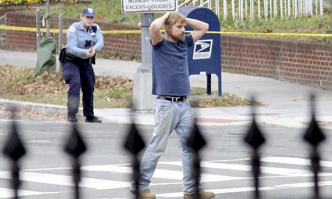 Edgar Maddison with his hands on his head, a police officer in the background