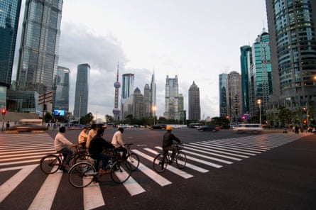 Cyclists going over a crossing with Shanghai’s skyscrapers in the background
