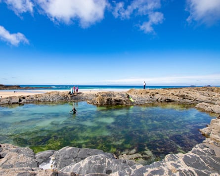 A child in a wetsuit wades in Treyarnon’s tidal pool.