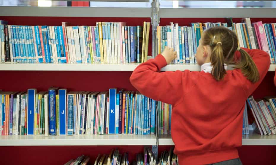A young british UK schoolgirl with pigtails browsing in the school library.