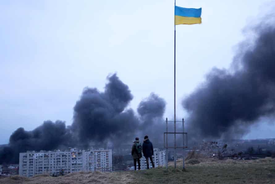 Des Ukrainiens devant un drapeau national après une frappe aérienne à Lviv, dans l'ouest de l'Ukraine