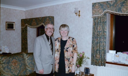 Judith and Peter, dressed in smart party clothes, in their living room with chintz curtains