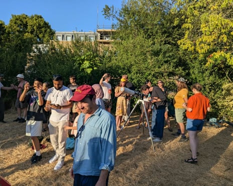 People gather in Brunswick Park, Camberwell, south London to watch the partial solar eclipse