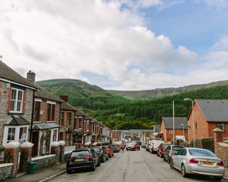 A village street with a woodland-covered mountain in the distance