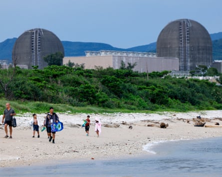 People walk on the beach with the Maanshan nuclear power plant in the background in Pingtu