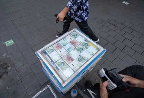 Man walks past vendor of Iranian rial notes
