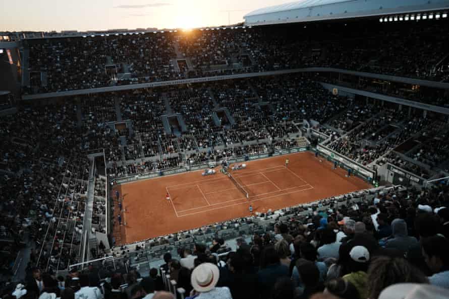 Spectators watch Novak Djokovic prepare to serve to Rafael Nadal.