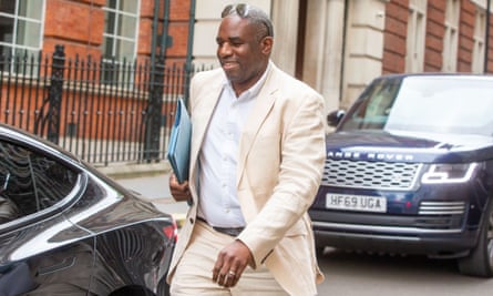 David Lammy, wearing a cream-coloured suit and white shirt, walks towards a car holding a manila folder