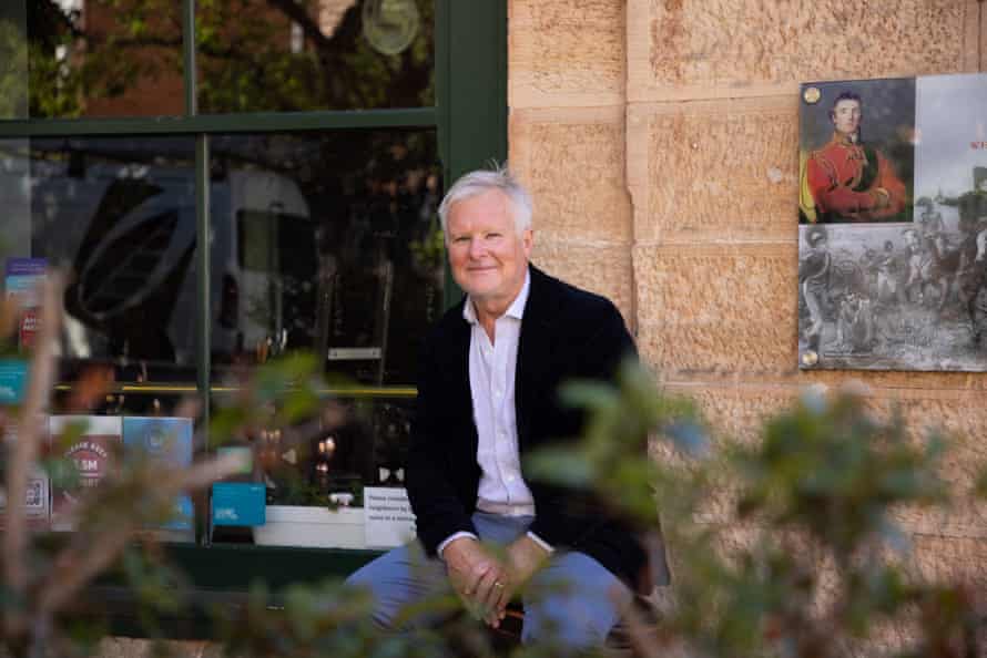 Grey-haired man sits in front of sandstone wall