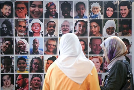 Two women look at headshots of those killed in the Grenfell fire.