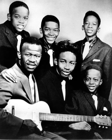 Black and white portrait of all the family together, with the dad holding a guitar