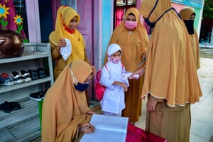 Teachers check the temperature of a pupil at a kindergarten in Banda Aceh.
