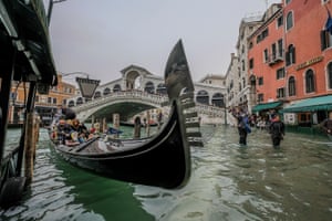 Tourists take the gondola in spite of the âacqua altaâ in Venice, Italy.