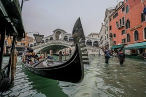 Tourists take the gondola in spite of the “acqua alta” in Venice, Italy.