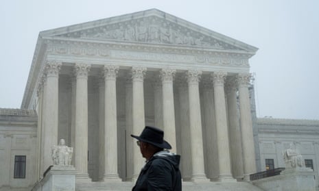 A man stands in front of the US supreme court building on a foggy and overcast day.