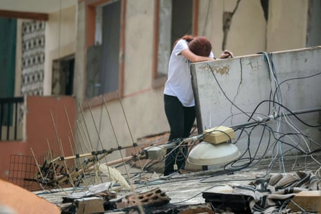 A woman cries while stood in debris.
