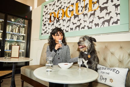 A woman and a dog sitting at a table.