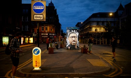 A mural of George Floyd painted on what appears to be a phone box, seen at dusk
