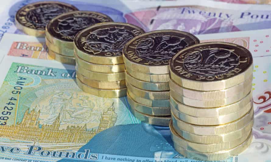 Stacks of one pound coins on British pound banknotes.