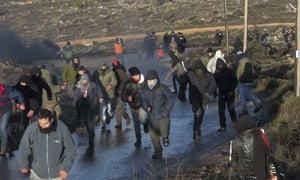 Settlers run from Israeli police outside the Amona outpost in the West Bank on Wednesday morning.