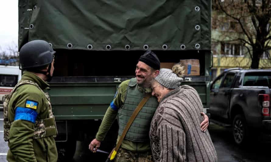 An old woman hugs a Ukrainian soldier in Bukha.