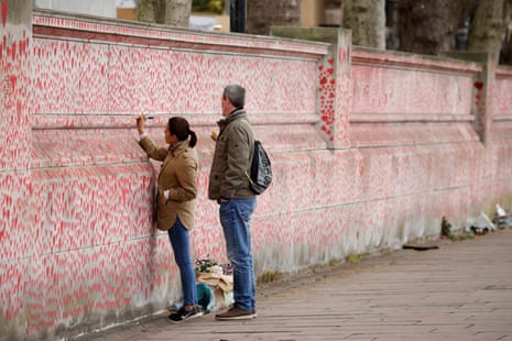 A woman drawing on the National Covid Memorial Wall on the embankment in London today.