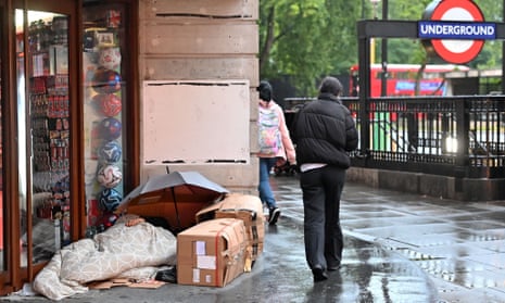 A pedestrian walks past a rough sleeper on Oxford Street, central London